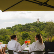 Vriendinnen proosten met cocktail op het terras met uitzicht op de heuvels.
