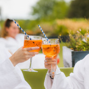 Gasten in badjas proosten met zomerse cocktail tijdens wellnessdag.