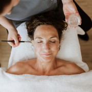 A woman receives a facial treatment from a Thermae 2000 wellness employee.